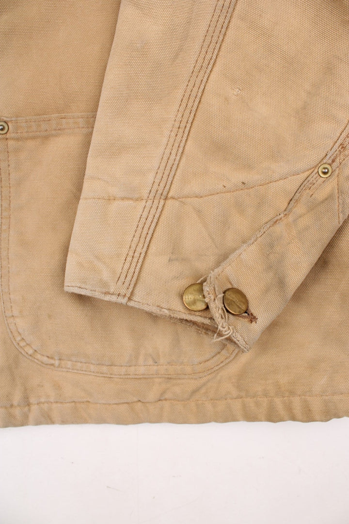 Carhartt Chore Jacket in a tan colourway with a brown corduroy collar. Buttons up and has multiple pockets, blanket lining, and has the logo embroidered on the front.