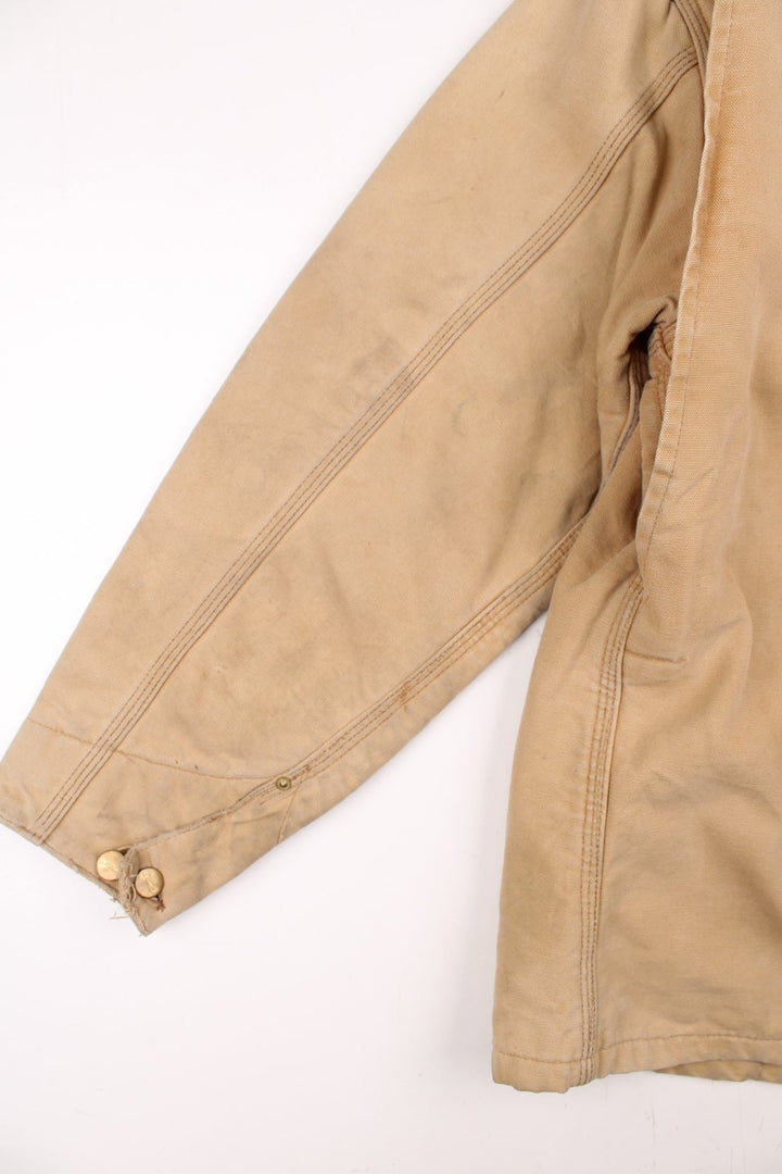 Carhartt Chore Jacket in a tan colourway with a brown corduroy collar. Buttons up and has multiple pockets, blanket lining, and has the logo embroidered on the front.