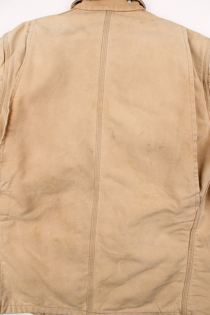 Carhartt Chore Jacket in a tan colourway with a brown corduroy collar. Buttons up and has multiple pockets, blanket lining, and has the logo embroidered on the front.