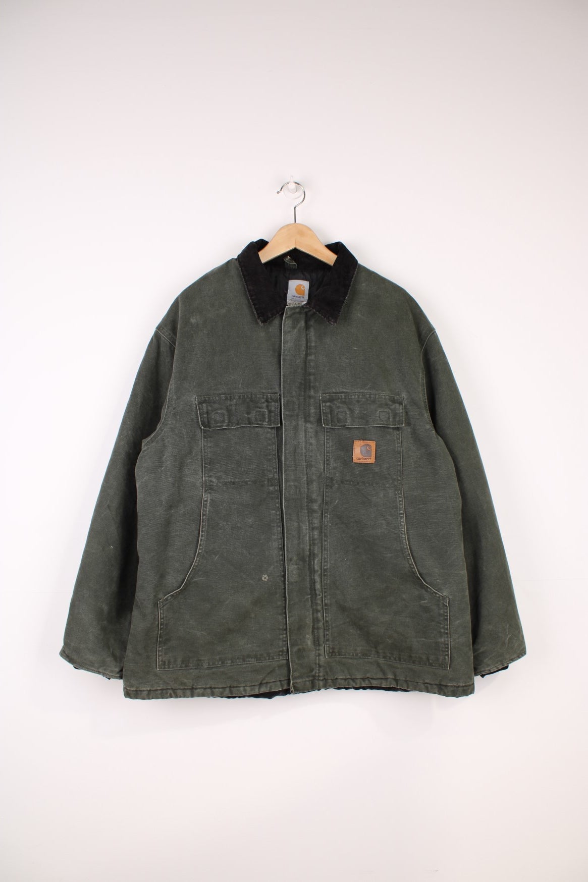 Carhartt Workwear Jacket in a khaki green colourway with a black corduroy collar, zip up with multiple pockets, insulated with a quilted lining, and has the logo embroidered on the front.