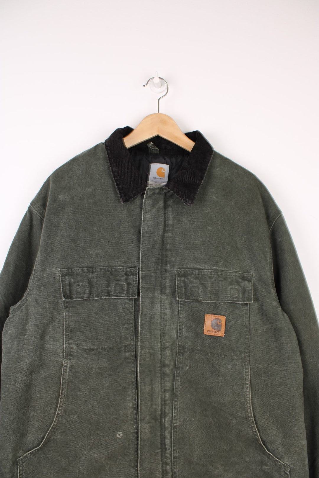 Carhartt Workwear Jacket in a khaki green colourway with a black corduroy collar, zip up with multiple pockets, insulated with a quilted lining, and has the logo embroidered on the front.