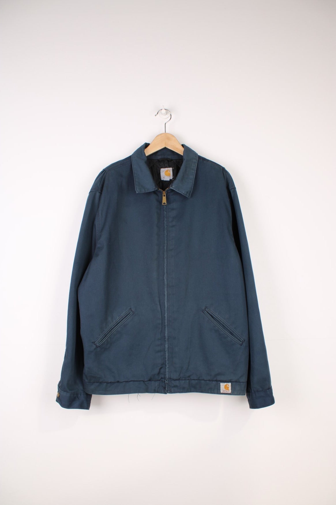 Carhartt Workwear Canvas Jacket in a blue colourway, zip up with side pockets, has a quilted lining, and the logo embroiderd on the front. 