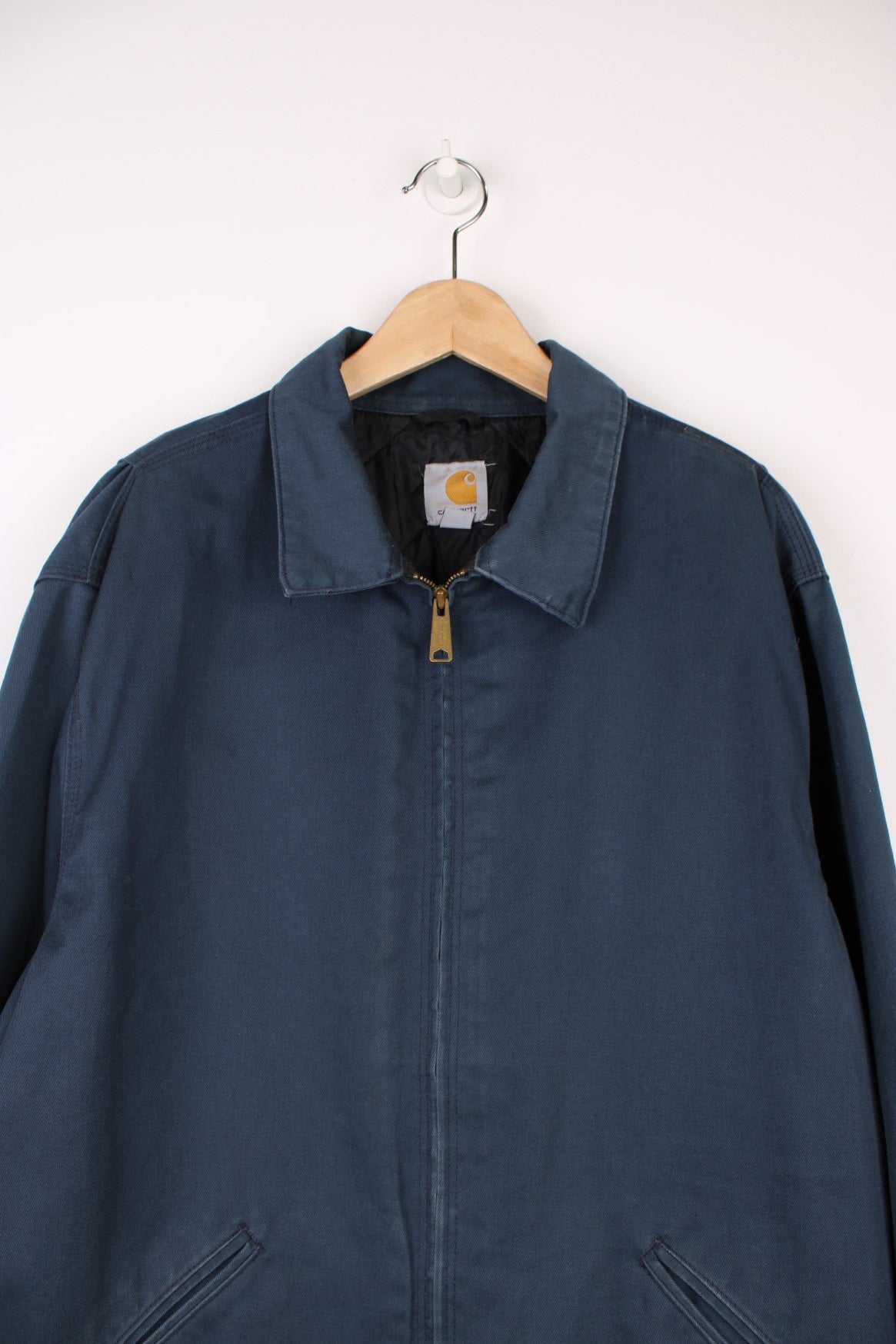 Carhartt Workwear Canvas Jacket in a blue colourway, zip up with side pockets, has a quilted lining, and the logo embroiderd on the front. 