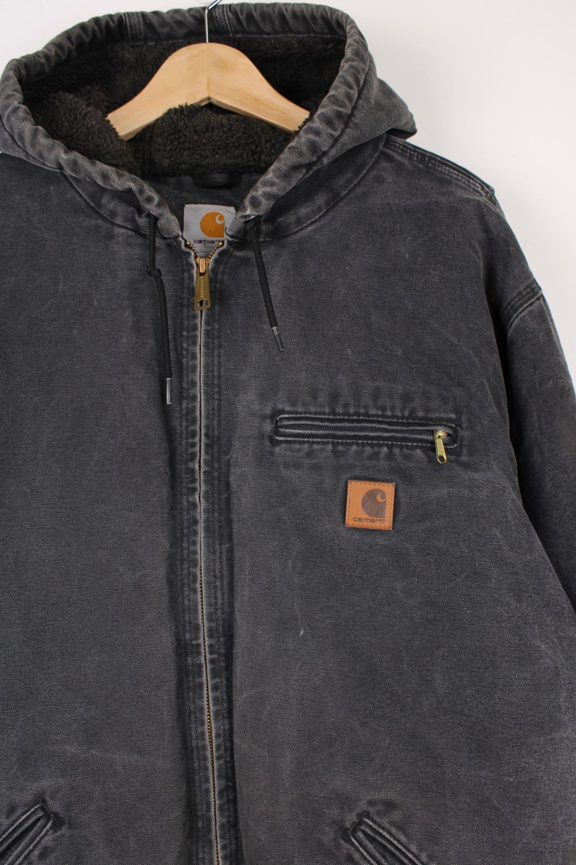 Carhartt Sierra Jacket in a grey colourway, zip up with multiple pockets, sherpa lining, hooded, and has the logo embroidered on the front. 