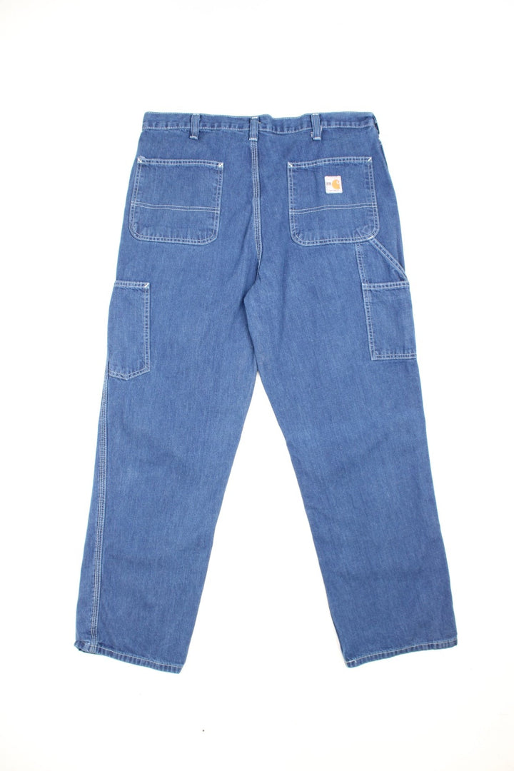 Carhartt Carpenter jeans in a dark blue denim, with white contrast stitching, multiple pockets and the logo embroidered on the back.