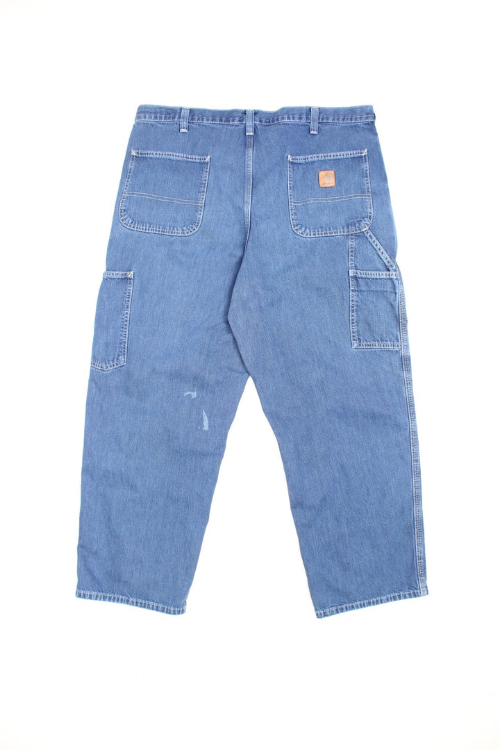 Carhartt Carpenter jeans in a faded blue denim, with white contrast stitching, multiple pockets and the logo embroidered on the back.