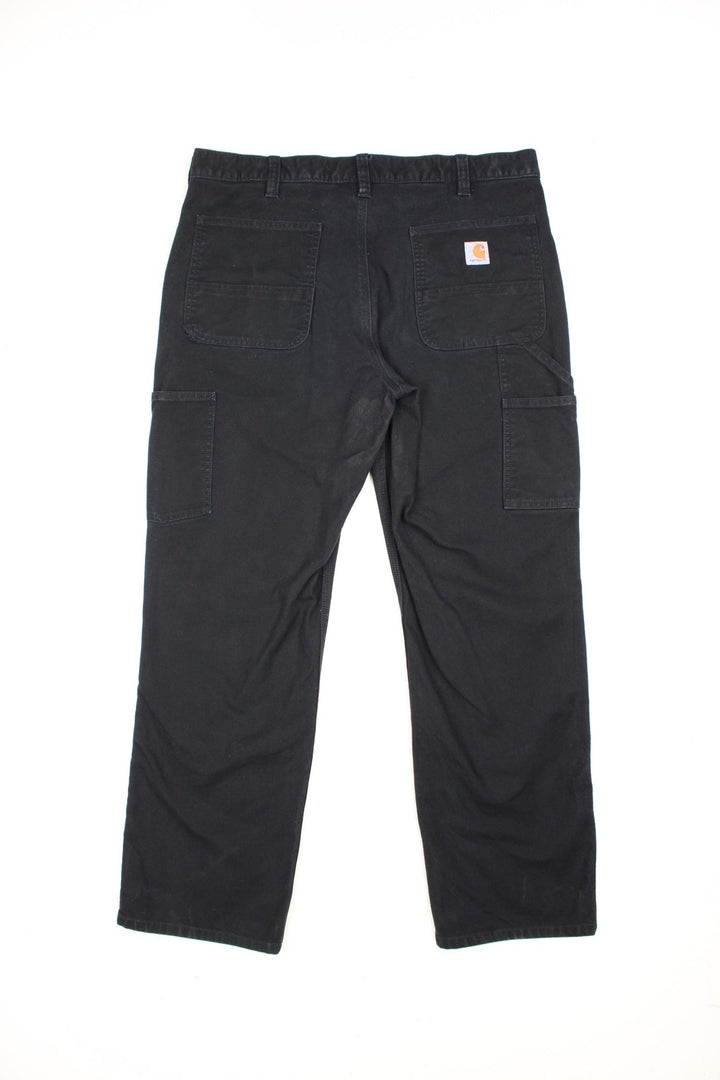 Carhartt all black relaxed fit carpenter jeans. Features double knees, multiple pockets and embroidered logo on the back.