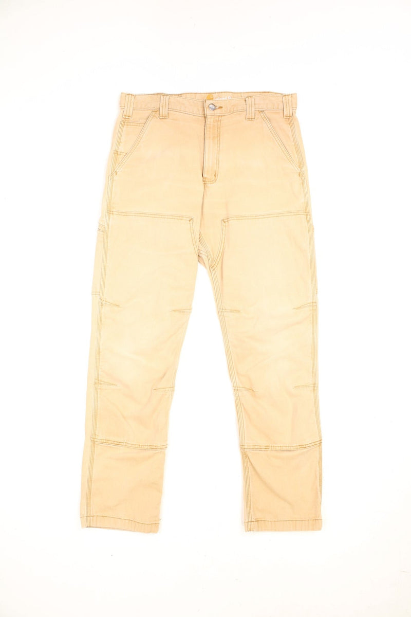 Carhartt tan relaxed fit carpenter jeans. Features double knees, multiple pockets and embroidered logo on the back