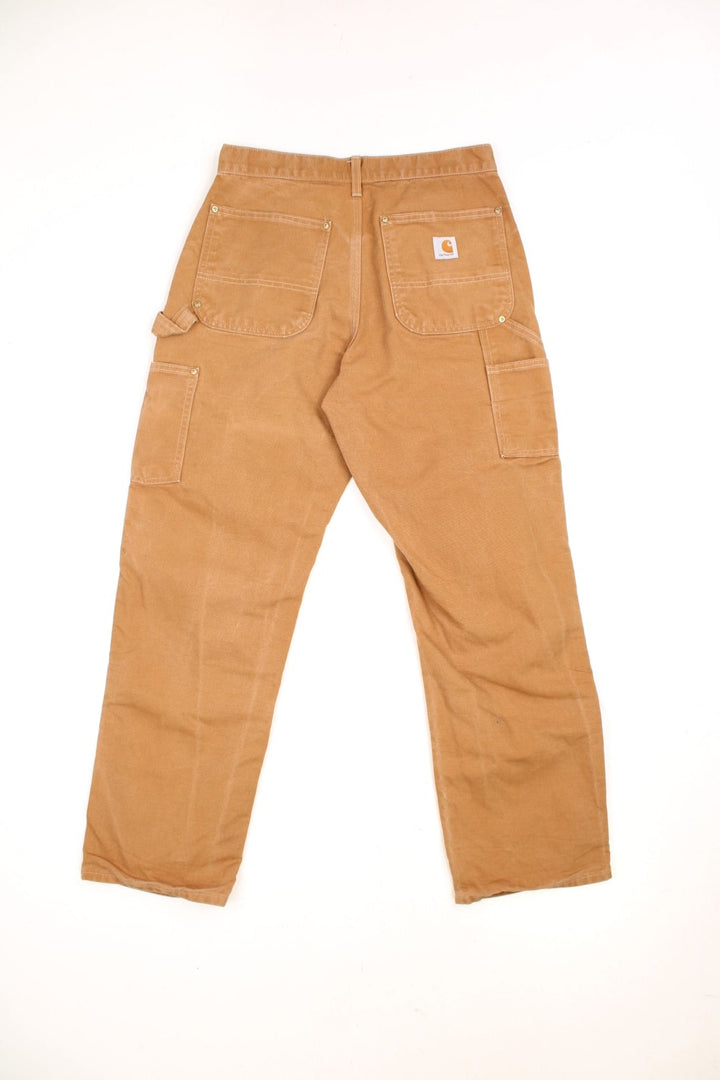 Carhartt brown loose original fit carpenter jeans. Features double knees, multiple pockets and embroidered logo on the back