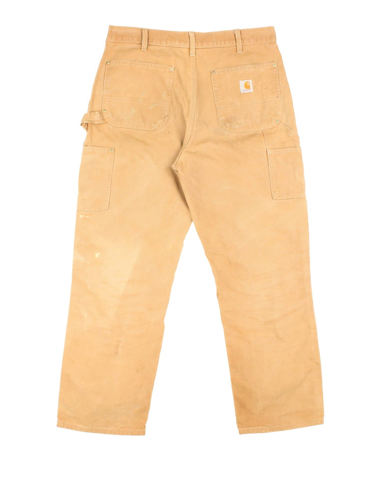 Carhartt Double Knee Jeans in a tan colourway with multiple pockets and the logo embroidered on the back.