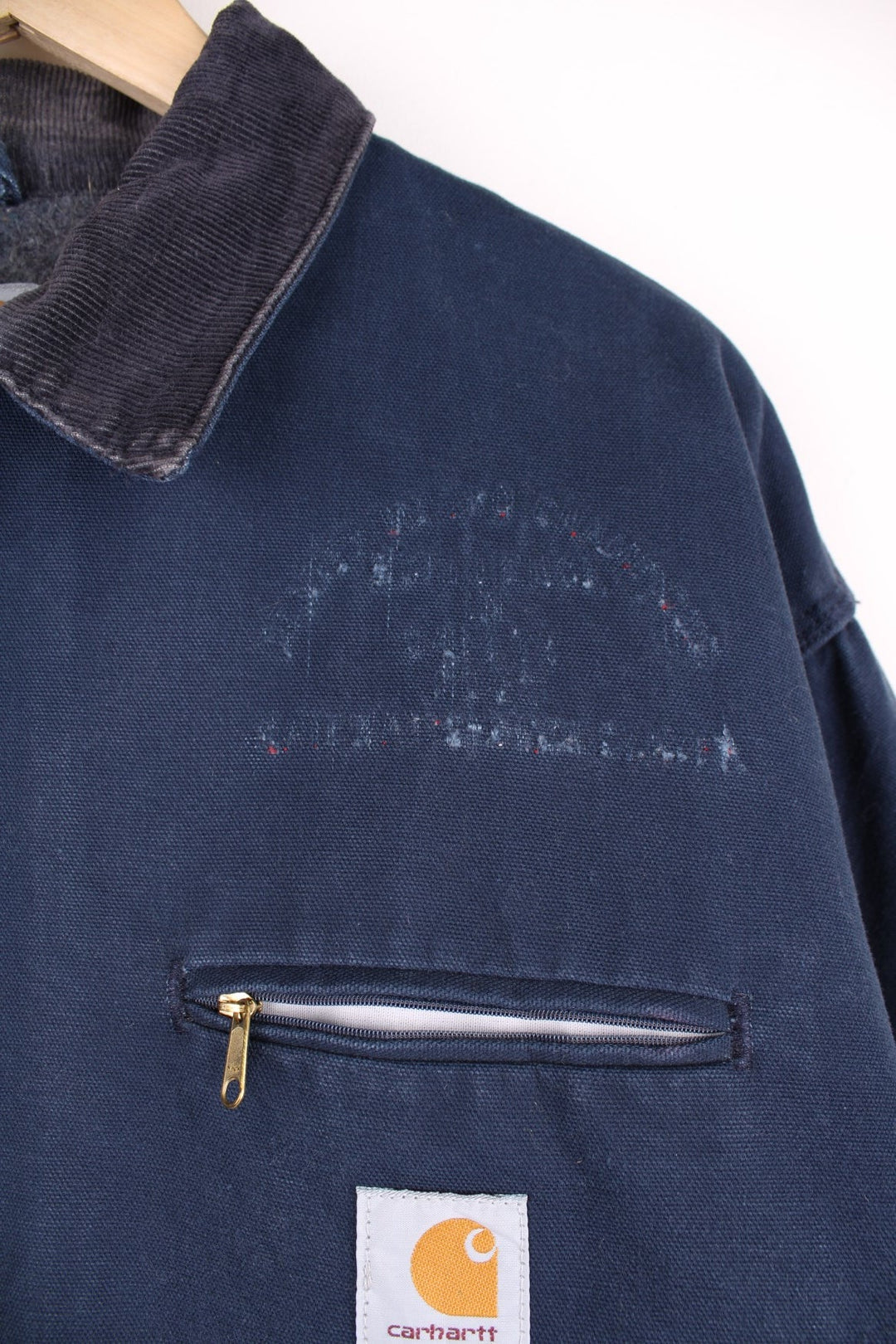 Carhartt Detroit Jacket in a navy blue colourway with a brown corduroy collar, zips up and has multiple pockets, blanket lining, and the logo embroidered on the front. 