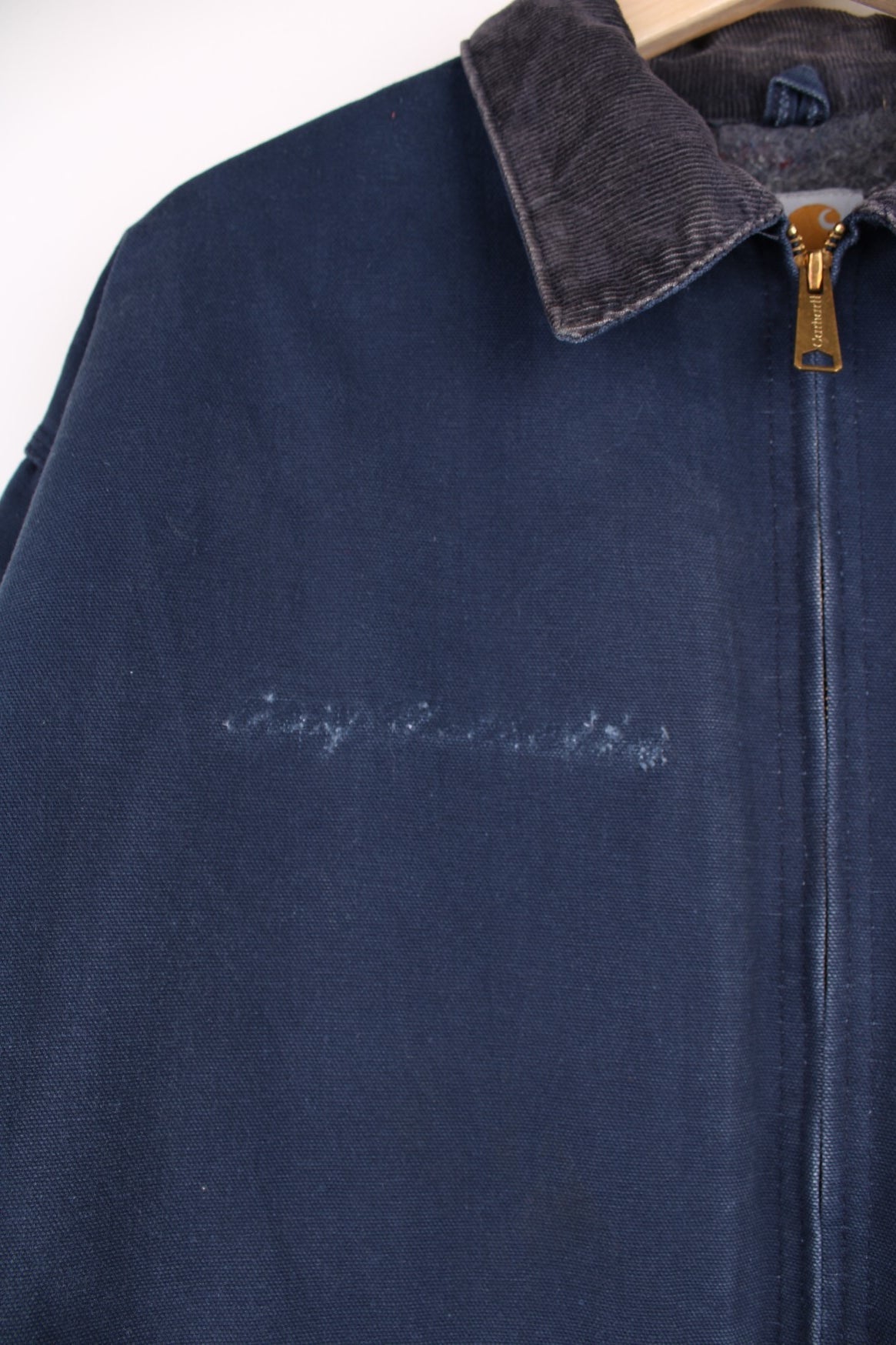 Carhartt Detroit Jacket in a navy blue colourway with a brown corduroy collar, zips up and has multiple pockets, blanket lining, and the logo embroidered on the front. 