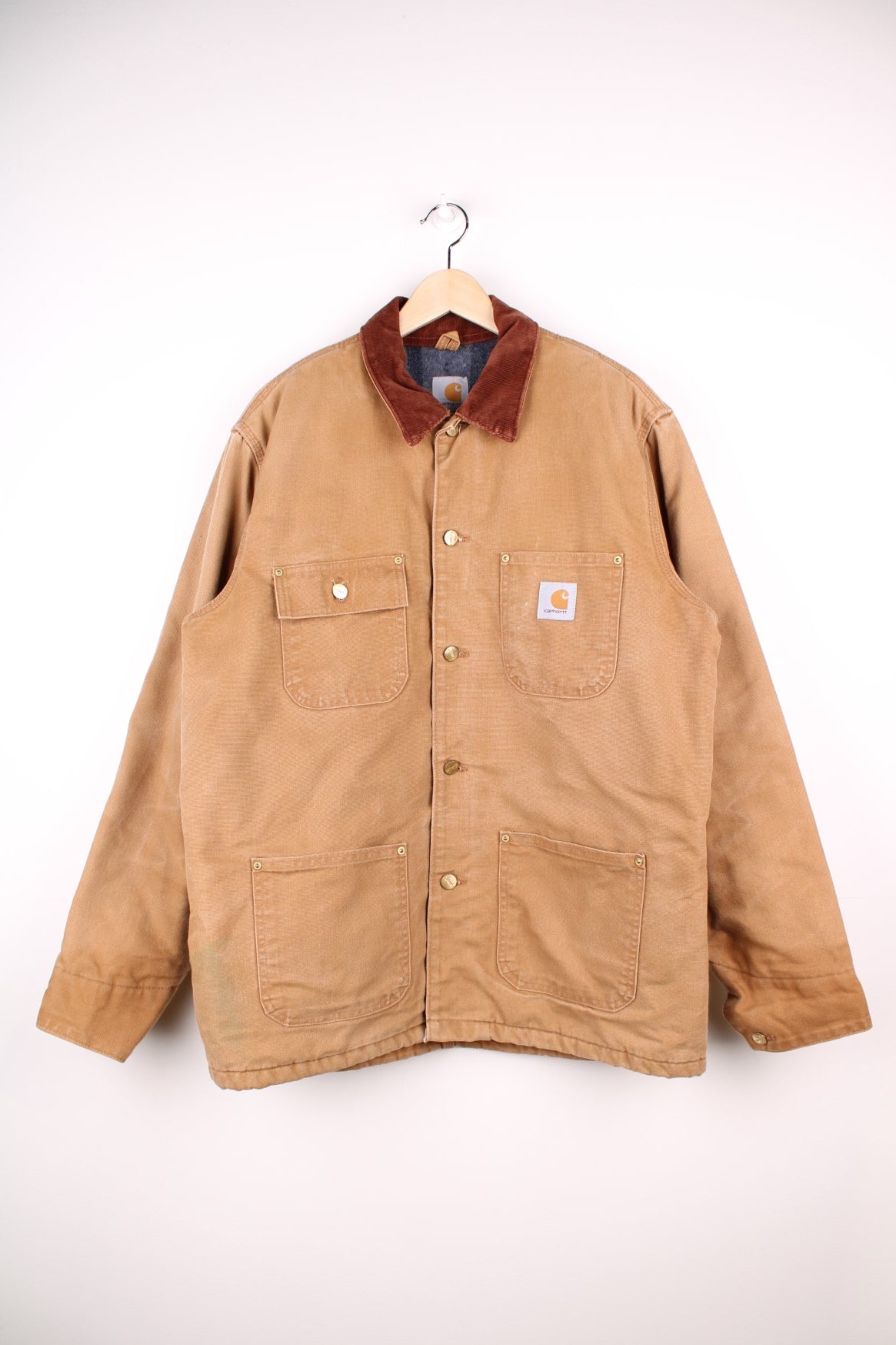 Carhartt Chore Jacket in a brown tanned colourway with a corduroy collar, buttons up and has multiple pockets, blanket lining, and the logo embroiderd on the front. 