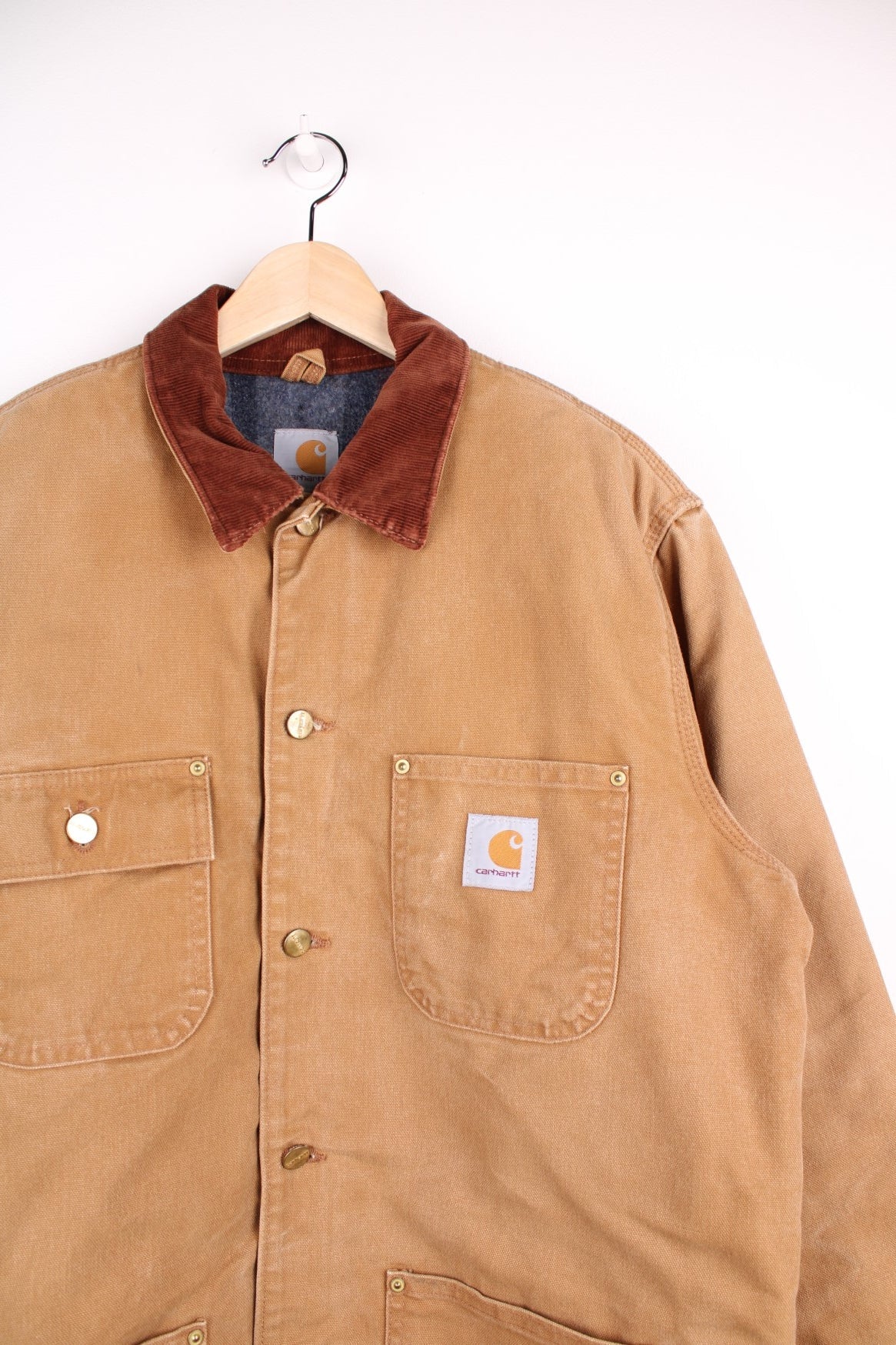 Carhartt Chore Jacket in a brown tanned colourway with a corduroy collar, buttons up and has multiple pockets, blanket lining, and the logo embroiderd on the front. 