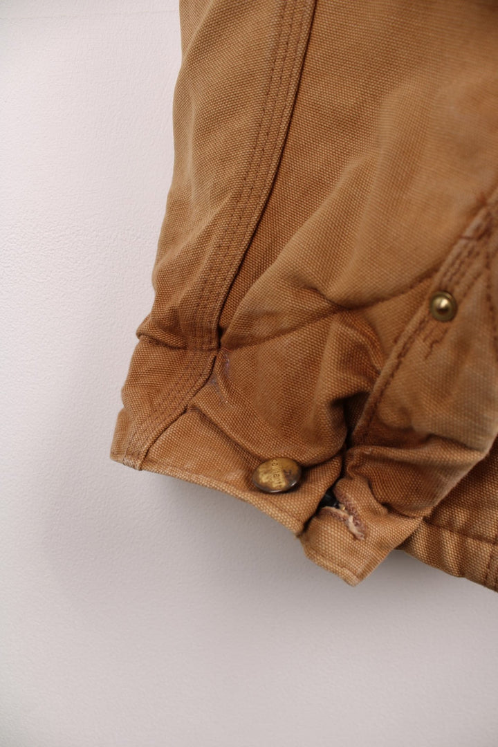 Carhartt Chore Jacket in a tanned colourway with a corduroy collar, buttons up and has multiple pockets, blanket lining, and the logo embroidered on the front. 