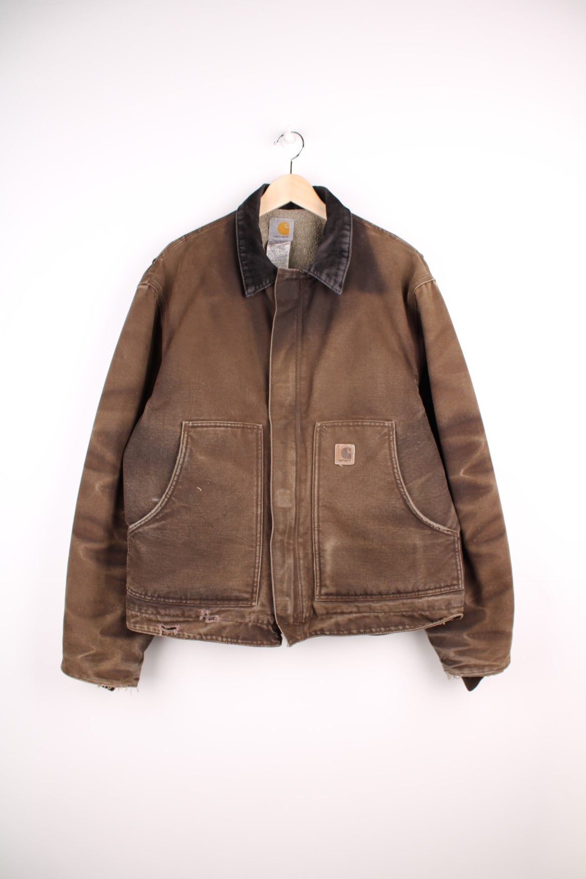 Carhartt Arctic Jacket in a faded brown colourway with a corduroy collar, zips up and has side pockets, insulated with a sherpa lining, and has the logo embroidered on the front.