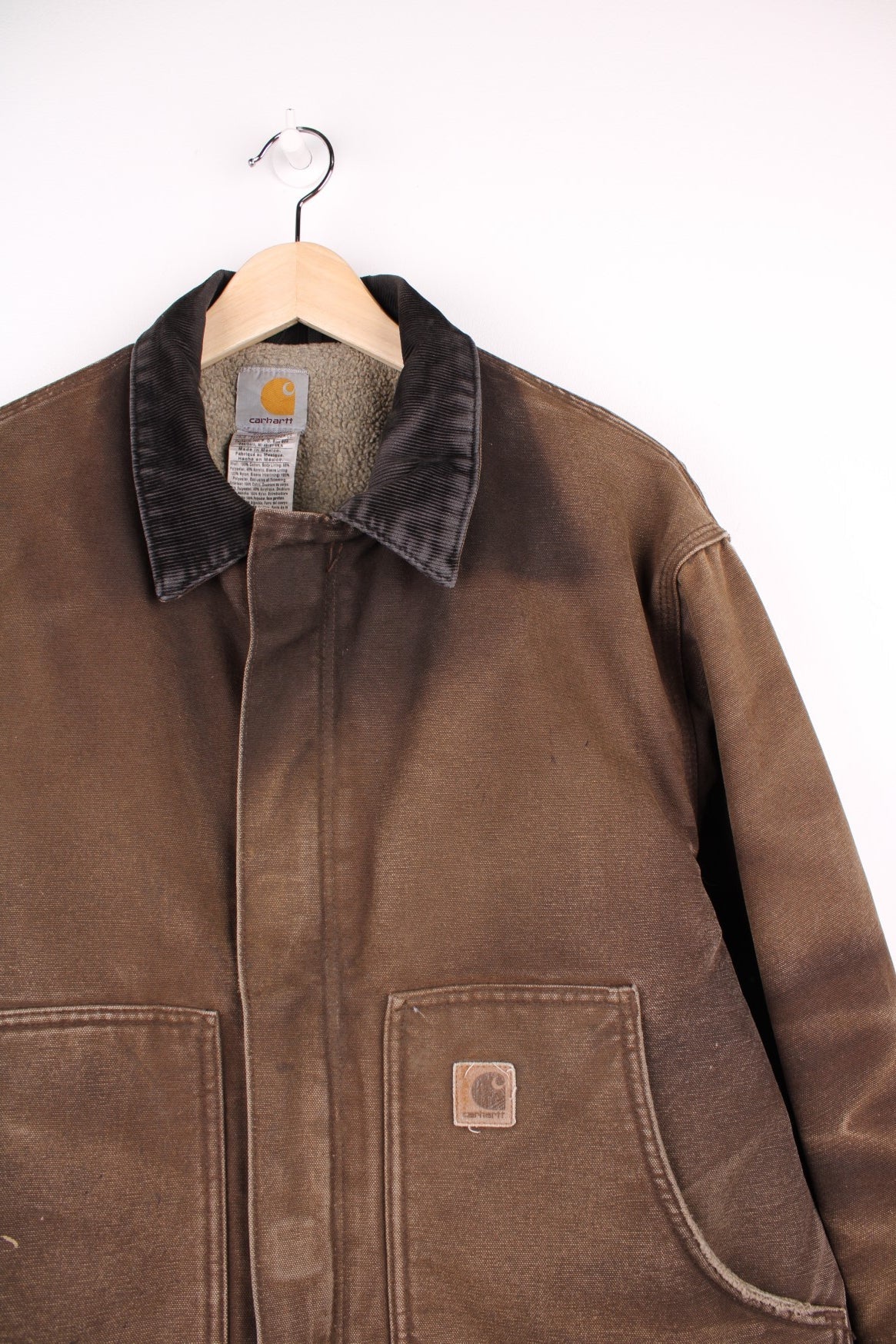 Carhartt Arctic Jacket in a faded brown colourway with a corduroy collar, zips up and has side pockets, insulated with a sherpa lining, and has the logo embroidered on the front.