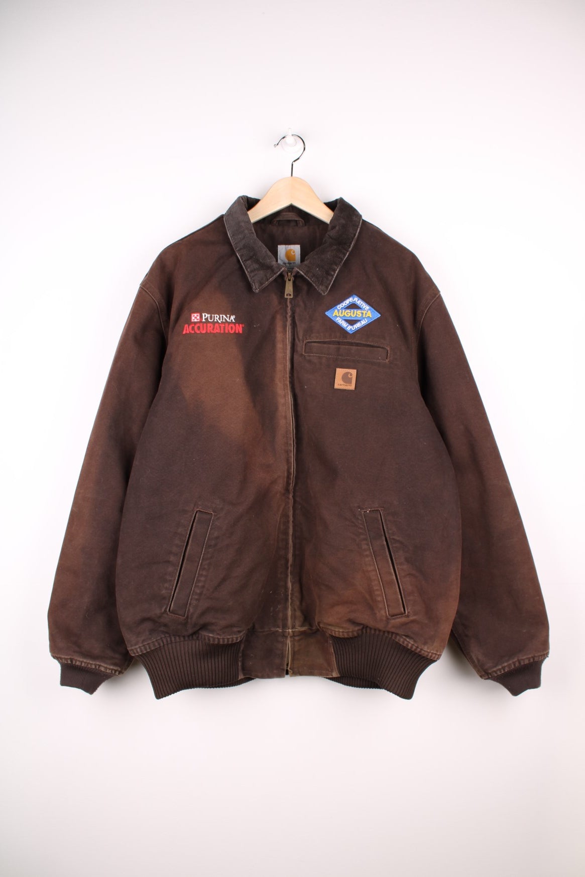 Carhartt Detroit Jacket in a sun burnt brown colourway with a corduroy collar, zips up and has multiple pockets, and company spell out logos embroidered on the front along the Carhartt logo.