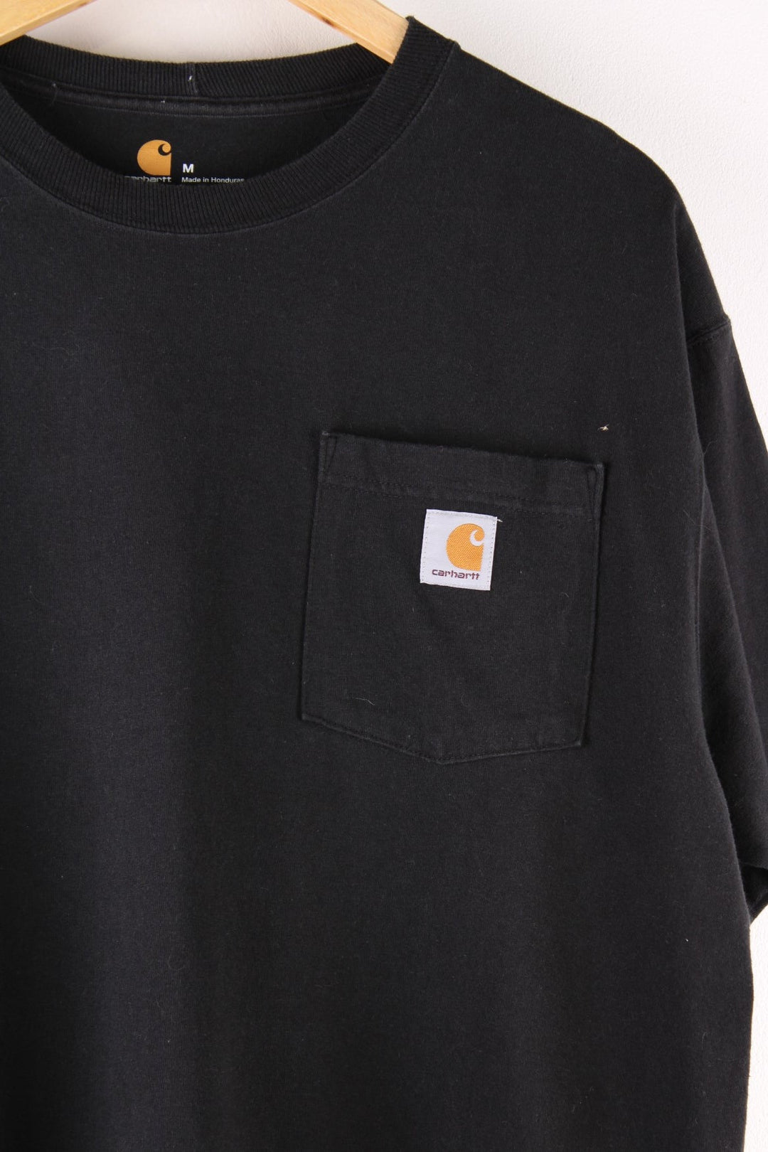 Carhartt T-Shirt in a black colourway with a patch pocket and logo stitched onto the front.