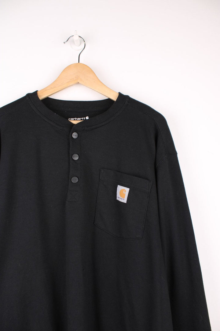 Carhartt 'loose fit' heavy weight black long sleeve top. Features signature logo on the chest pocket and three button fastening 