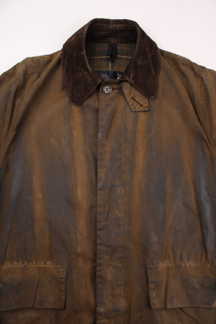 Barbour 3/4 length waxed jacket in brown with multiple pockets, button closure, and a corduroy collar.