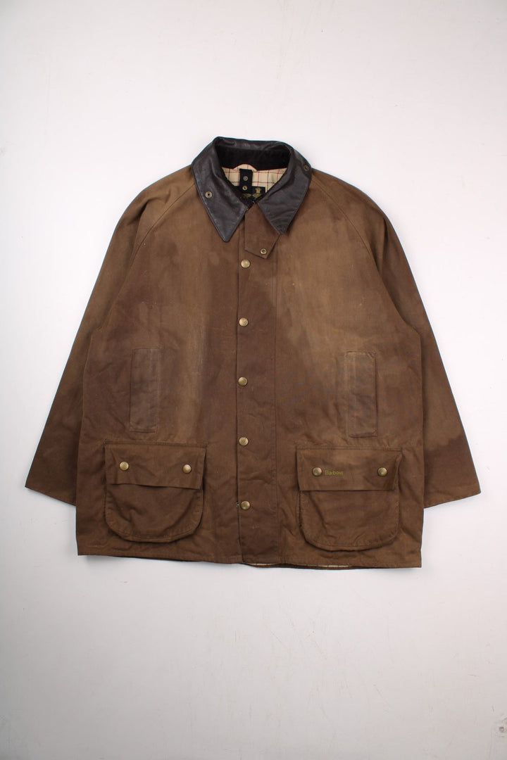 Barbour waxed jacket in brown with multiple pockets, zip closure, and a leather collar.