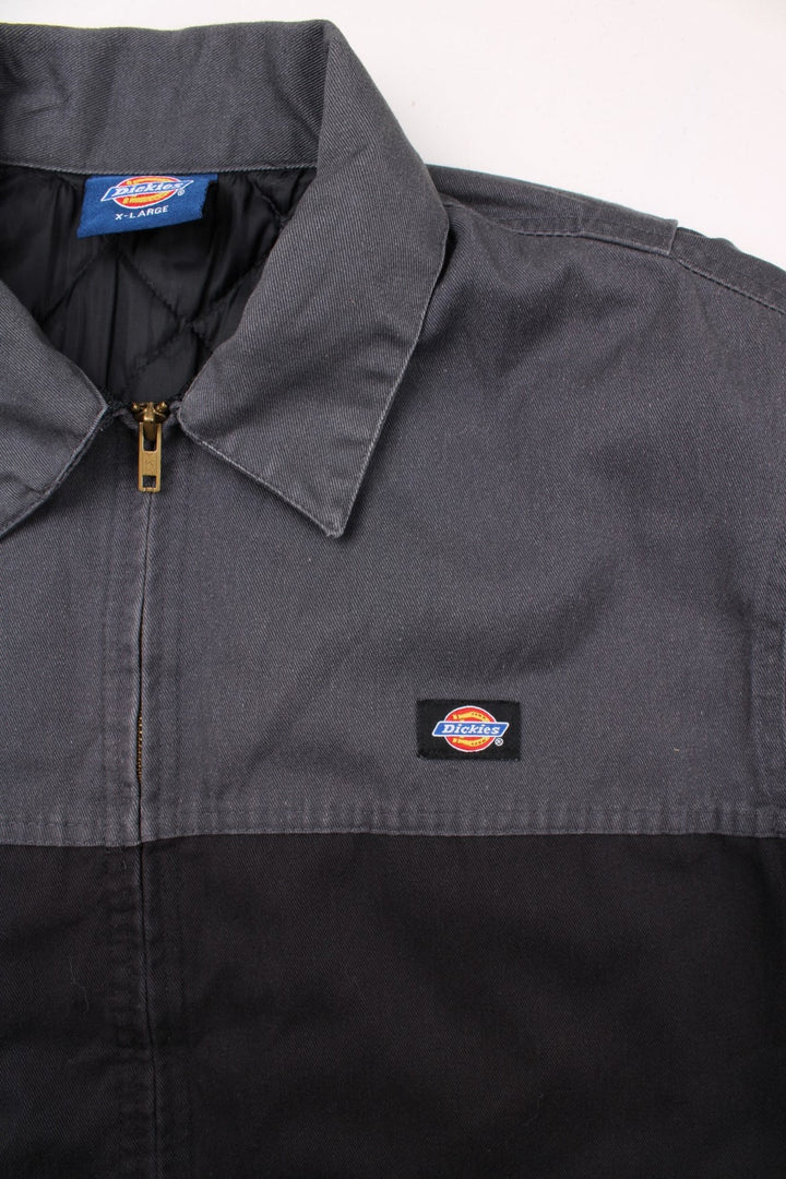 Dickies quilt-lined two-tone Eisenhower jacket in black and grey with two pockets, zip closure, and a small logo patch on the chest.