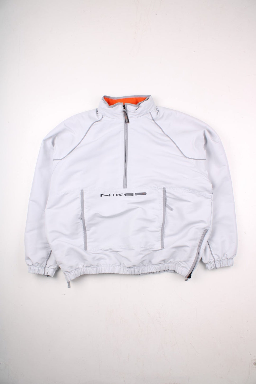 Nike 1/2 zip windbreaker jacket in pale grey with 2 pockets, mesh lining, zipped side vents, and small logos front and back.