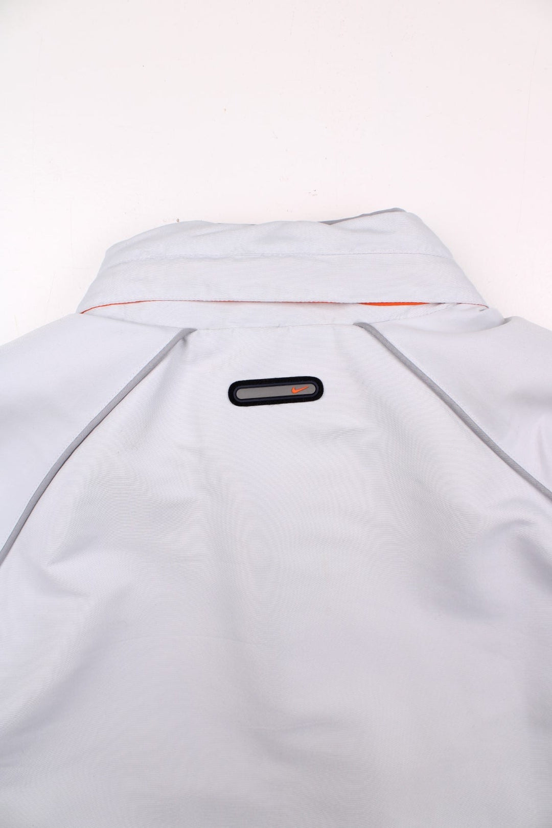 Nike 1/2 zip windbreaker jacket in pale grey with 2 pockets, mesh lining, zipped side vents, and small logos front and back.