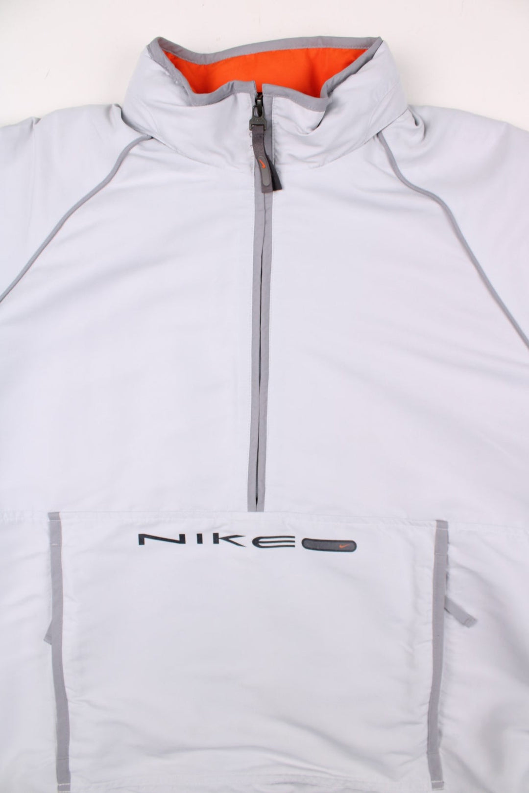 Nike 1/2 zip windbreaker jacket in pale grey with 2 pockets, mesh lining, zipped side vents, and small logos front and back.