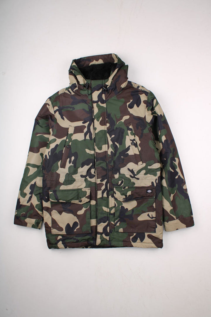 Dickies camouflage parka in green and brown - quilt-lined, with zip and snap closure, multiple pockets, and a sherpa-lined hood. Hood would have originally had detachable fur trim but this is missing.