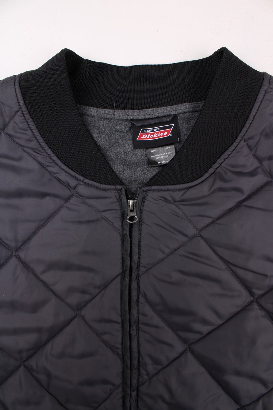 Dickies diamond quilted jacket in grey with ribbed black collar and cuffs, zip closure, two pockets, an elasticated hem, and a small logo patch on the front.