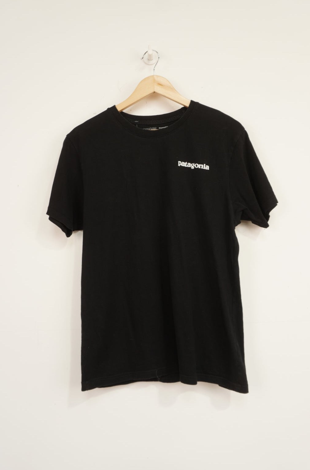 Patagonia black responsibili-tee with printed spell-out logo on the front and signature mountain graphic on the back 