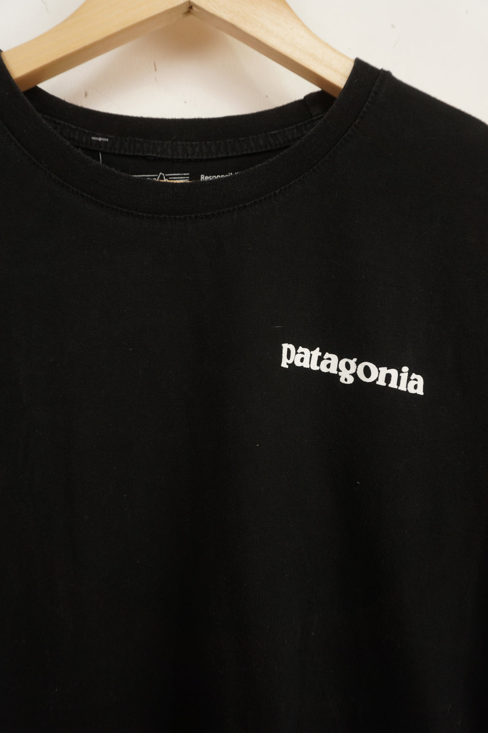 Patagonia black responsibili-tee with printed spell-out logo on the front and signature mountain graphic on the back 