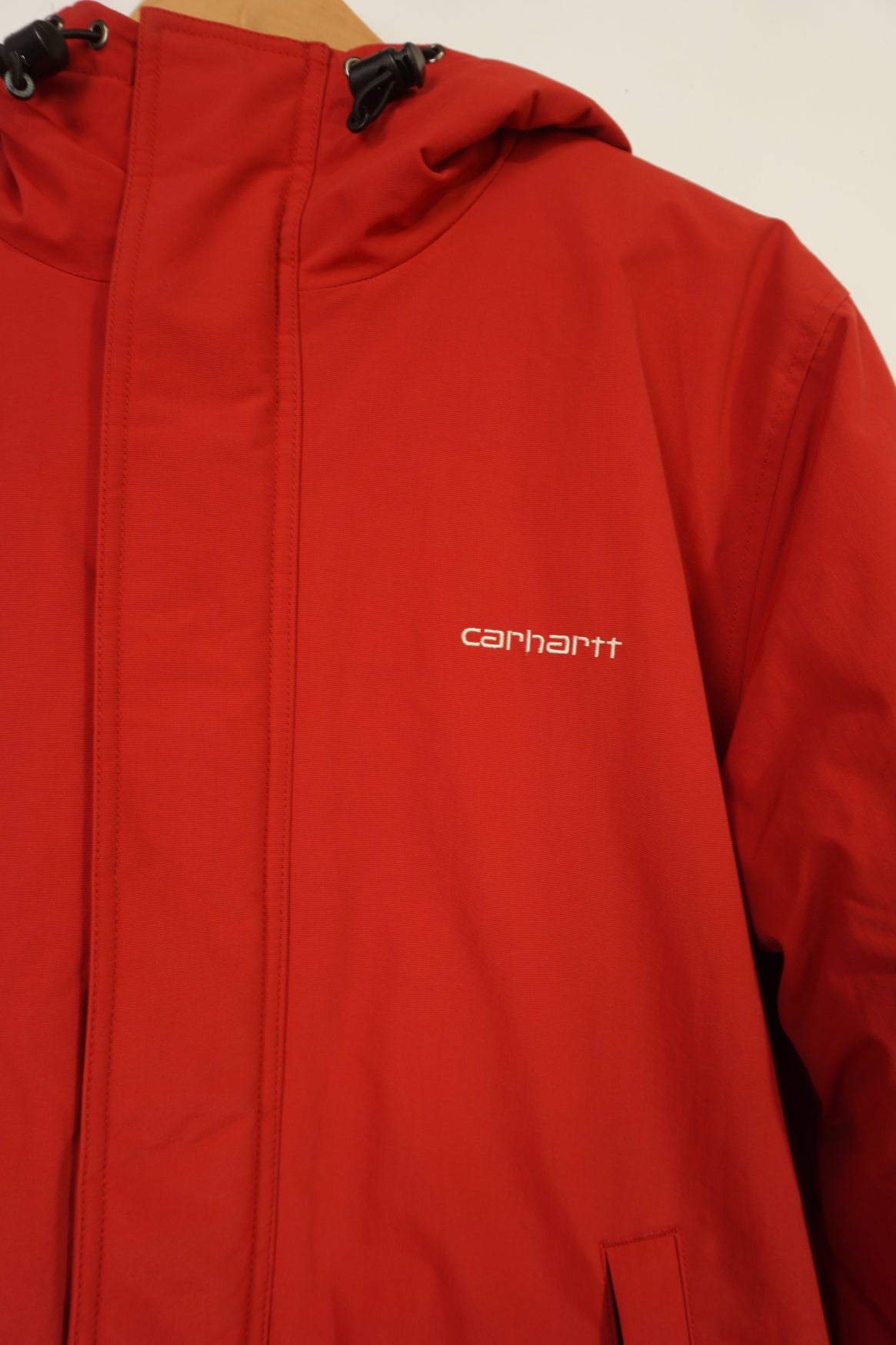 Red Carhartt outdoor coat with zip up pockets and embroidered logo on the chest