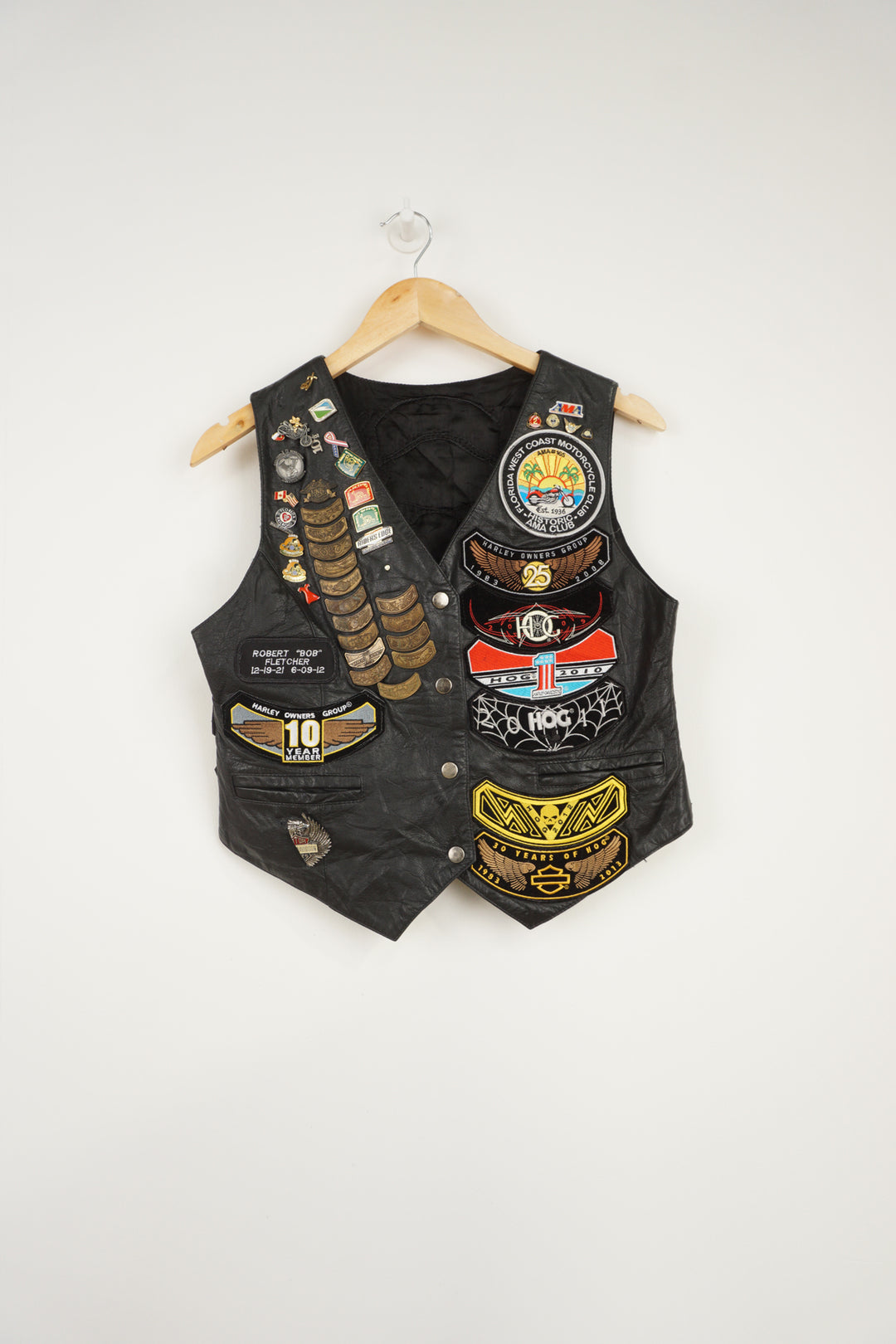 Women's vintage Harley Davidson Owners Group black leather vest with lots of commemorative patches and pins