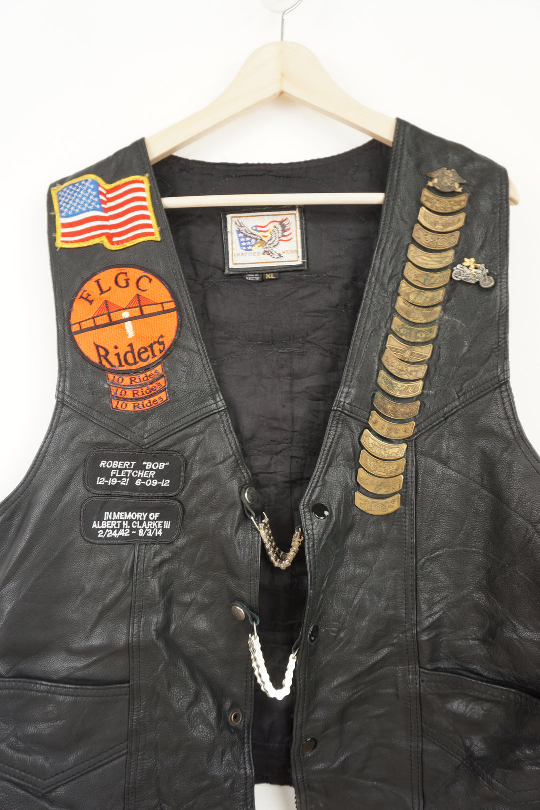 Men's vintage Harley Davidson Owners Group black leather vest with lots of commemorative patches, pins and bike chain details