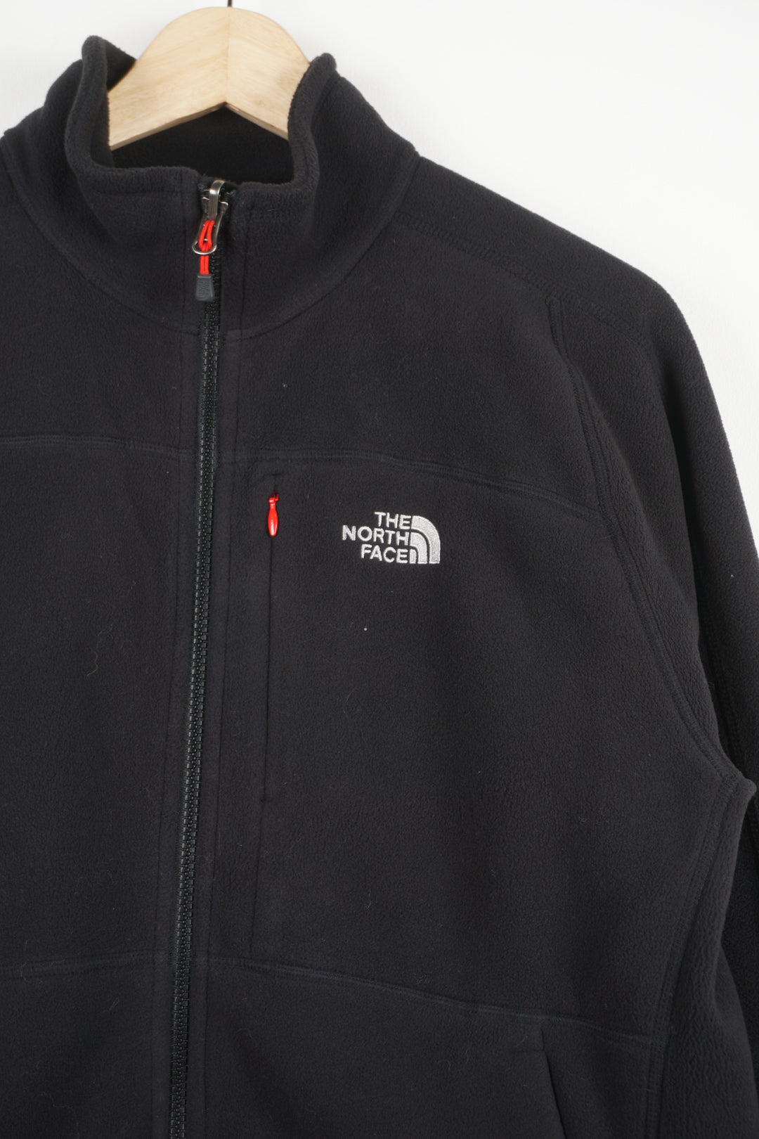 The North Face black zip through fleece, features zip up pockets and embroidered logo on the chest