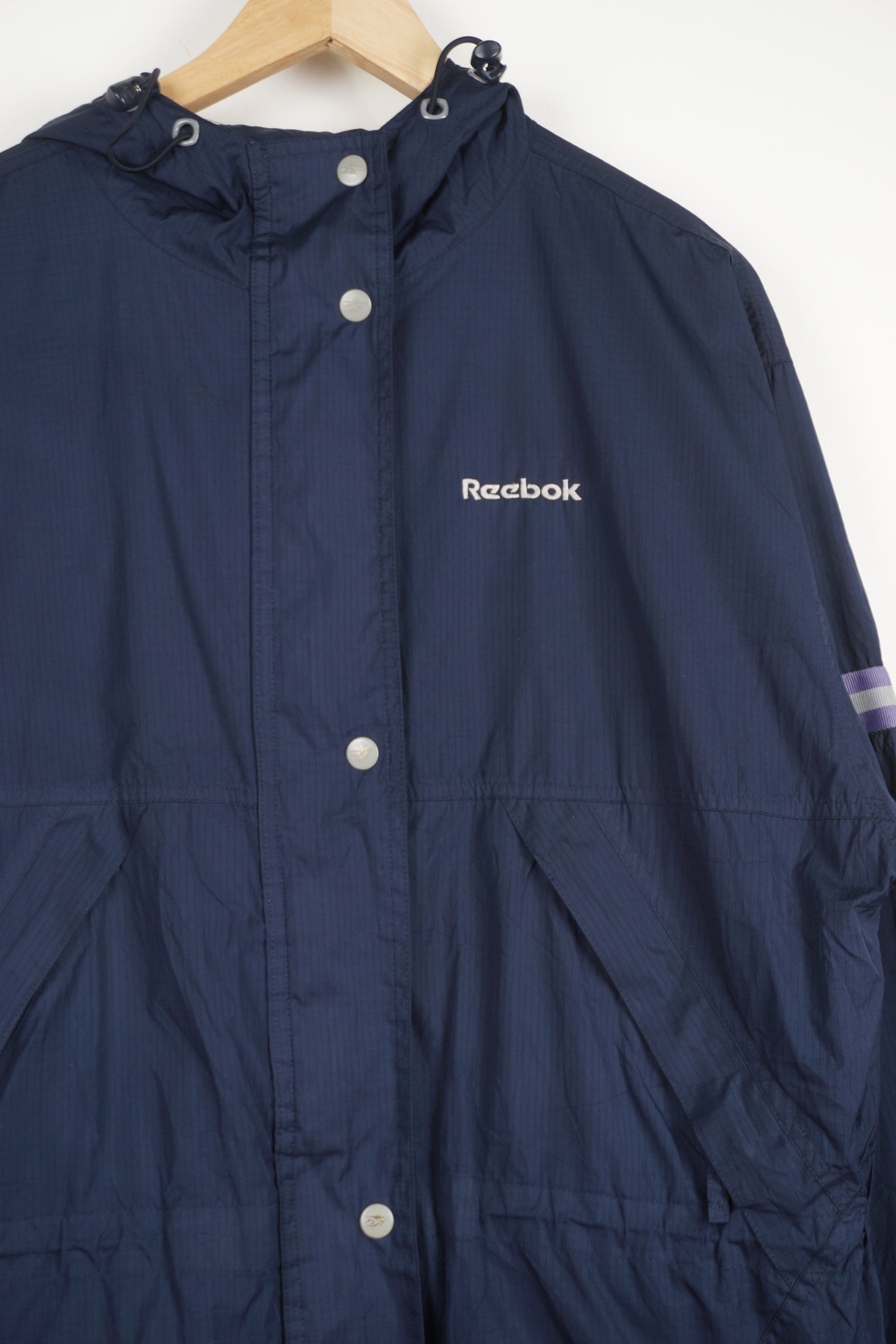 Reebok navy blue zip through windbreaker jacket features embroidered logo on the chest and reflective ribbon on the sleeves and back 