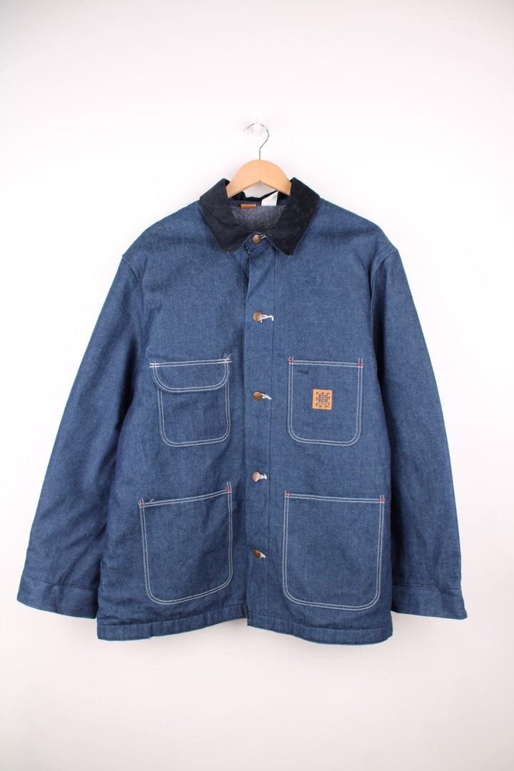 Big Ben by Wrangler Denim Chore Coat in a blue colourway with a black corduroy collar, button up with multiple pockets, has a blanket lining, and the logo embroidered on the front. 