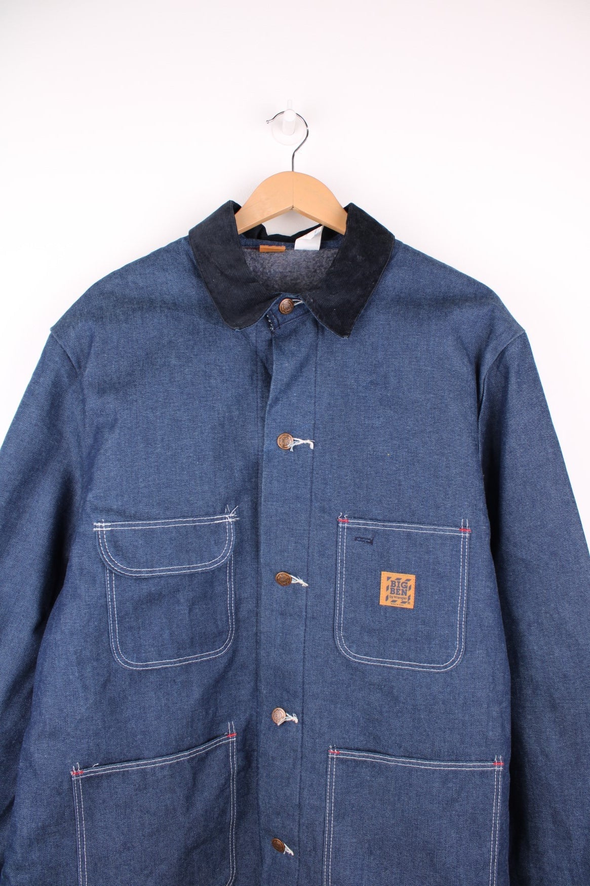 Big Ben by Wrangler Denim Chore Coat in a blue colourway with a black corduroy collar, button up with multiple pockets, has a blanket lining, and the logo embroidered on the front. 