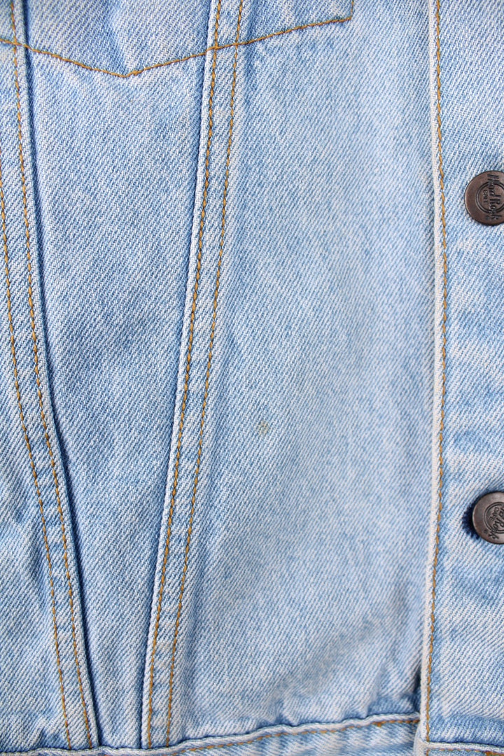 Hard Rock Cafe Denim Jacket in a light blue colourway, button up with multiple pockets, and has the logo embroidered on the back. 