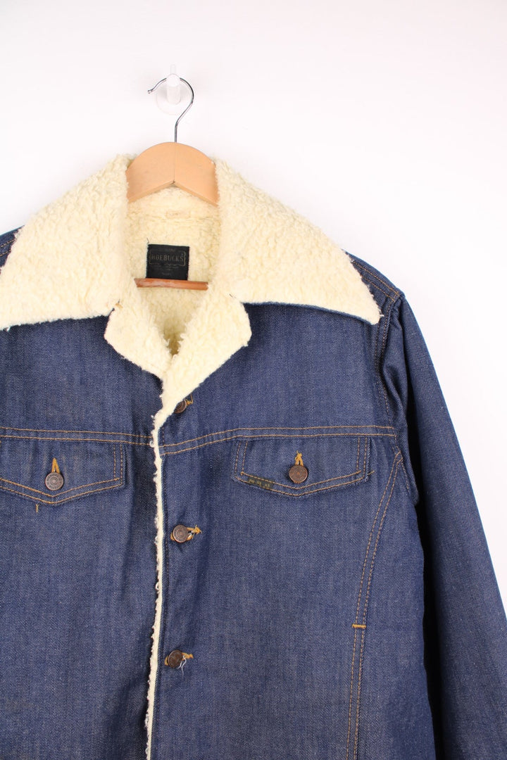 Vintage 70's Sears Roebuck Denim Sherpa Jacket in a blue colourway with a cream sherpa lining, button up with a camp collar, has multiple pockets and the logo embroidered on the front. 