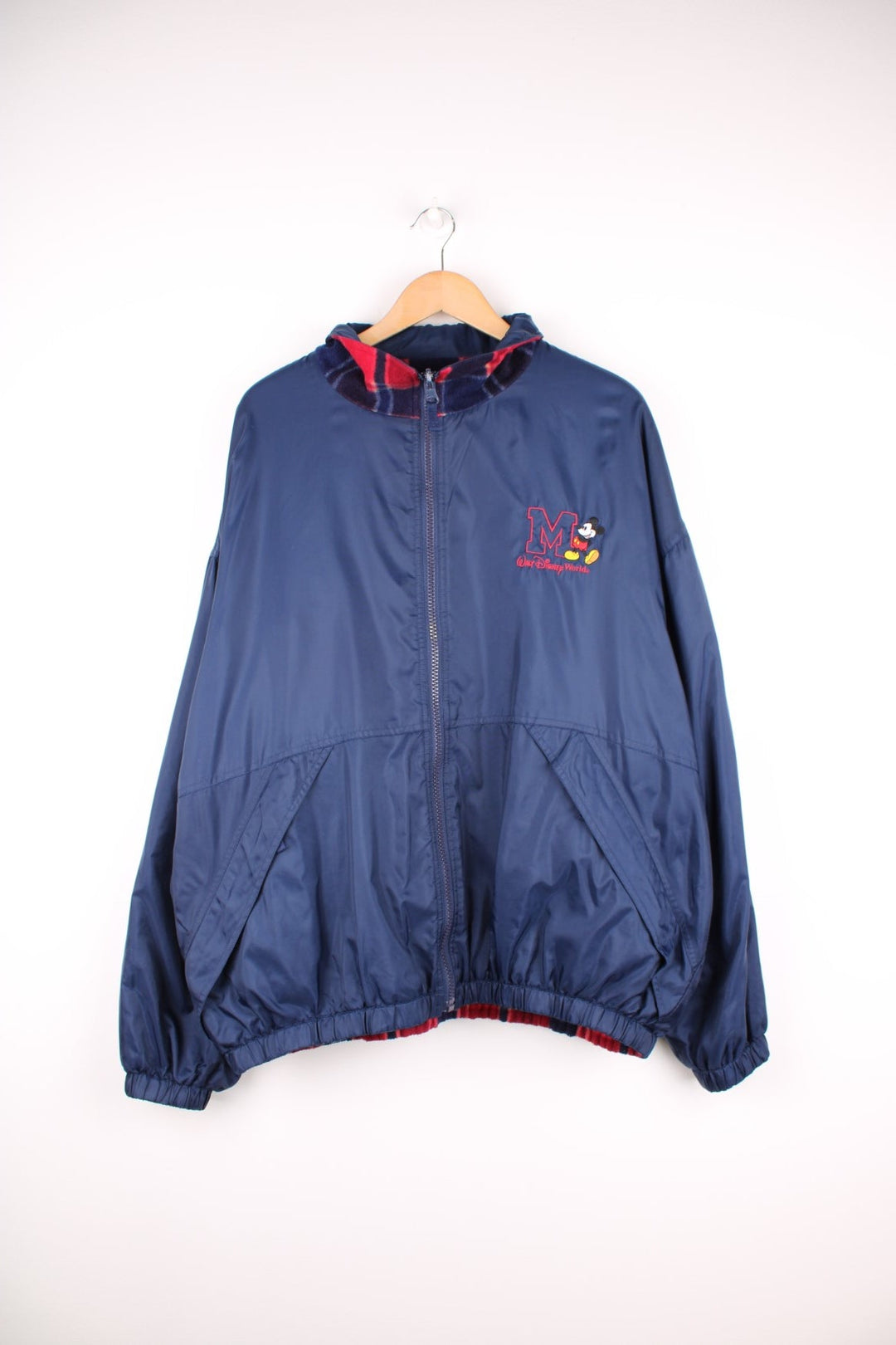 Disney World Reversible Jacket in either a navy blue waterpoof or a tartan fleece colourway, zip up with side pockets, and on the waterproof side has the logo embroidered on the chest. 