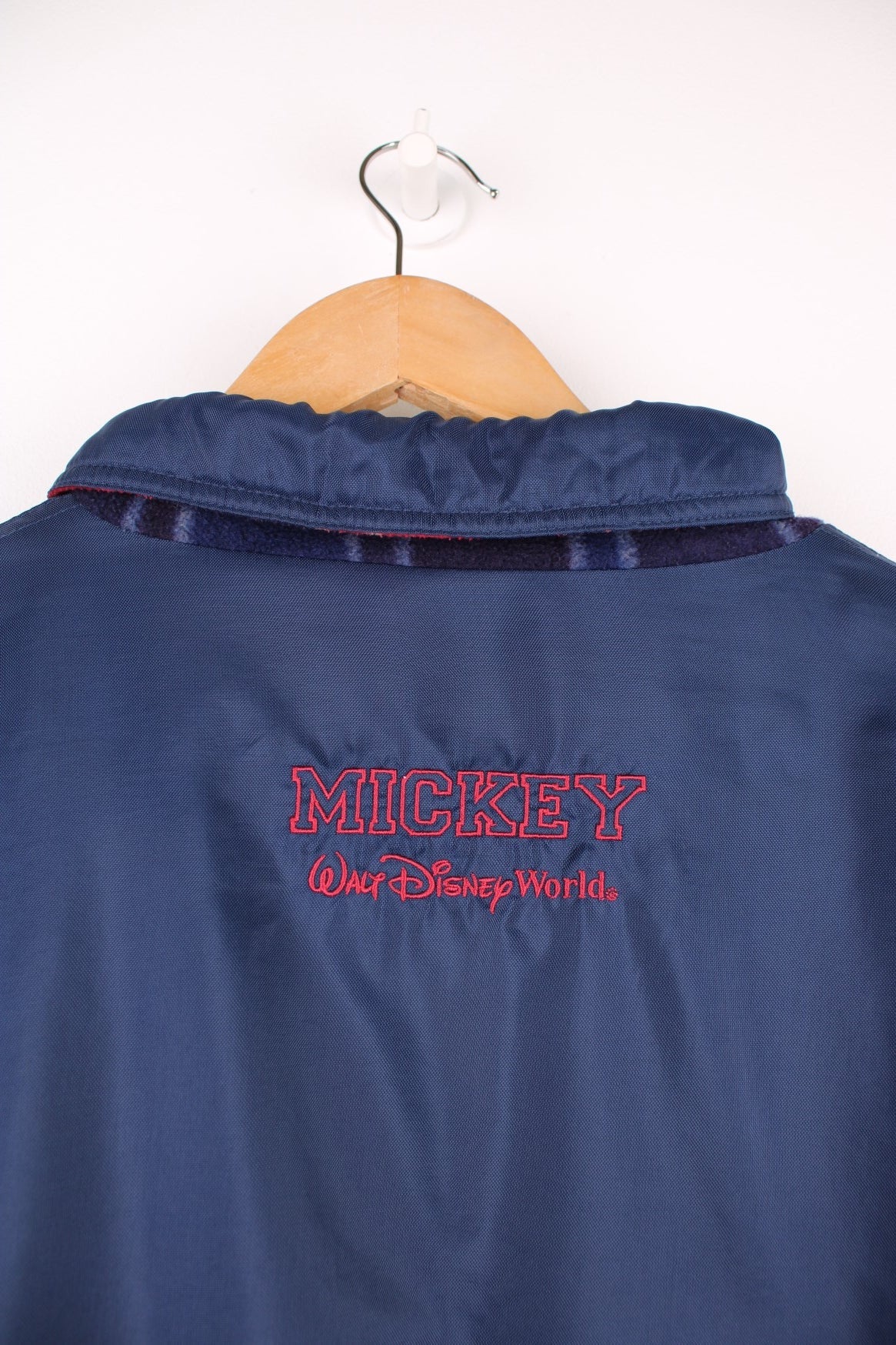 Disney World Reversible Jacket in either a navy blue waterpoof or a tartan fleece colourway, zip up with side pockets, and on the waterproof side has the logo embroidered on the chest. 