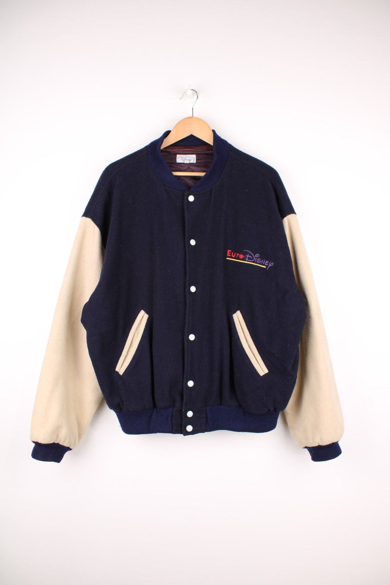 1992 Euro Disney Opening Crew Varsity Jacket in a navy blue and cream colourway, button up with side pockets, has a quilted lining, and has 'opening crew' spell out embroidered on the back alongside Mickey Mouse.