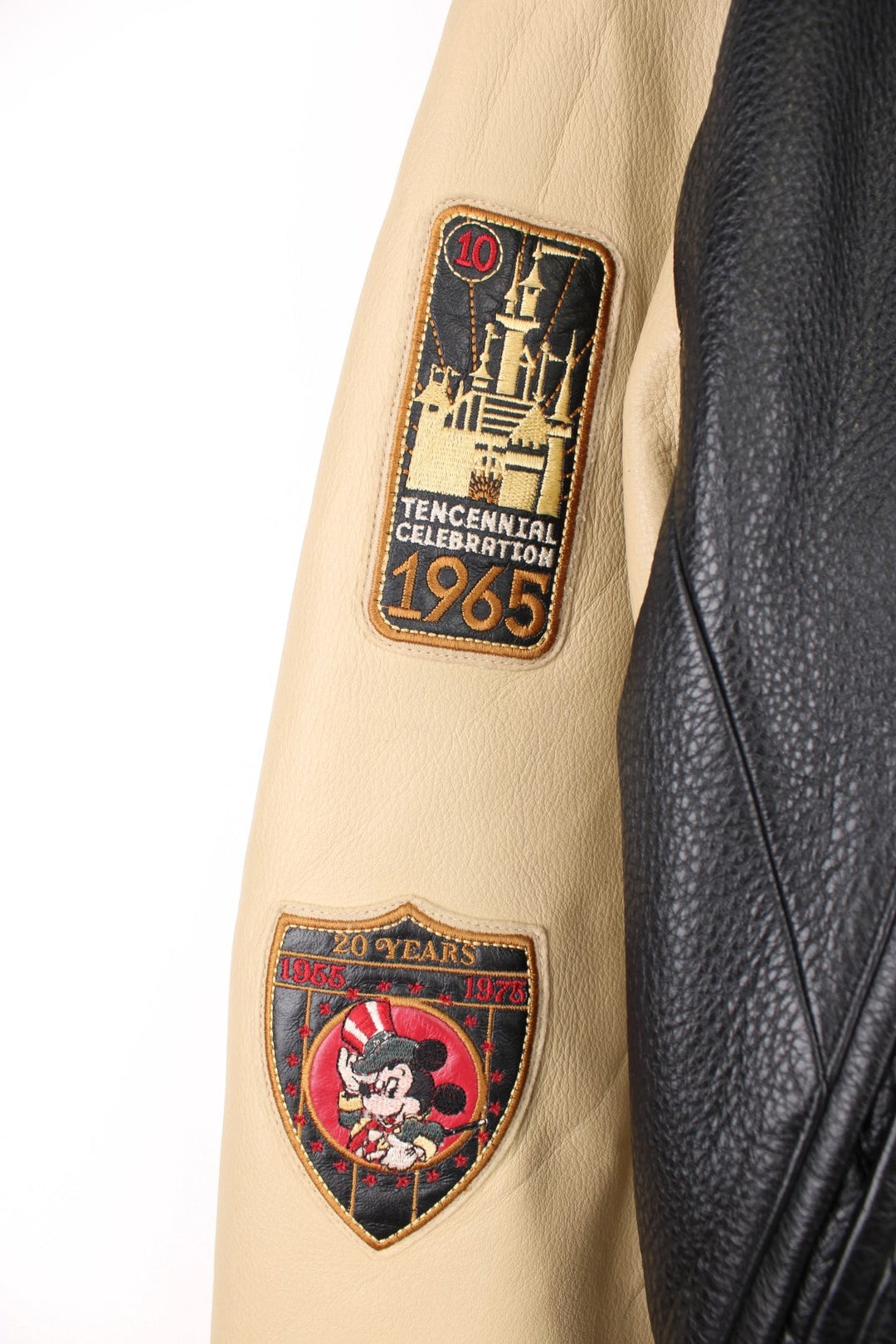 Disneyland Resort 50th Year Anniversary Leather Varsity Jacket in a black and cream colourway, zip up with side pockets, badges going down the sleeves, and has the spell out and Mickey Mouse embroidered on the front and back. 