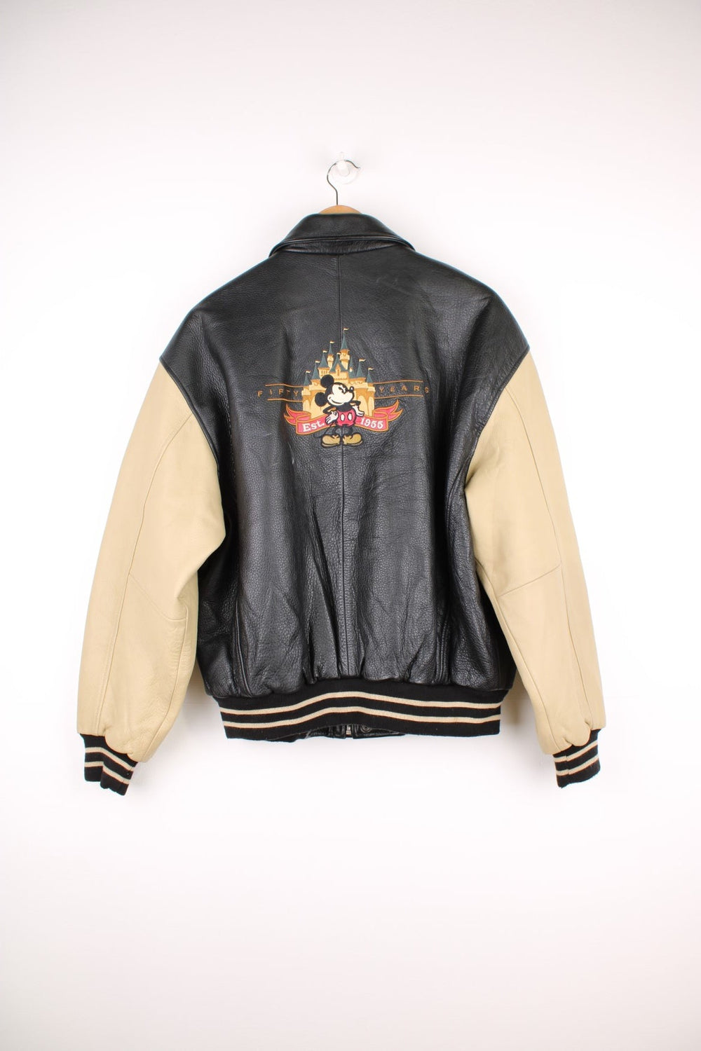 Disneyland Resort 50th Year Anniversary Leather Varsity Jacket in a black and cream colourway, zip up with side pockets, badges going down the sleeves, and has the spell out and Mickey Mouse embroidered on the front and back. 