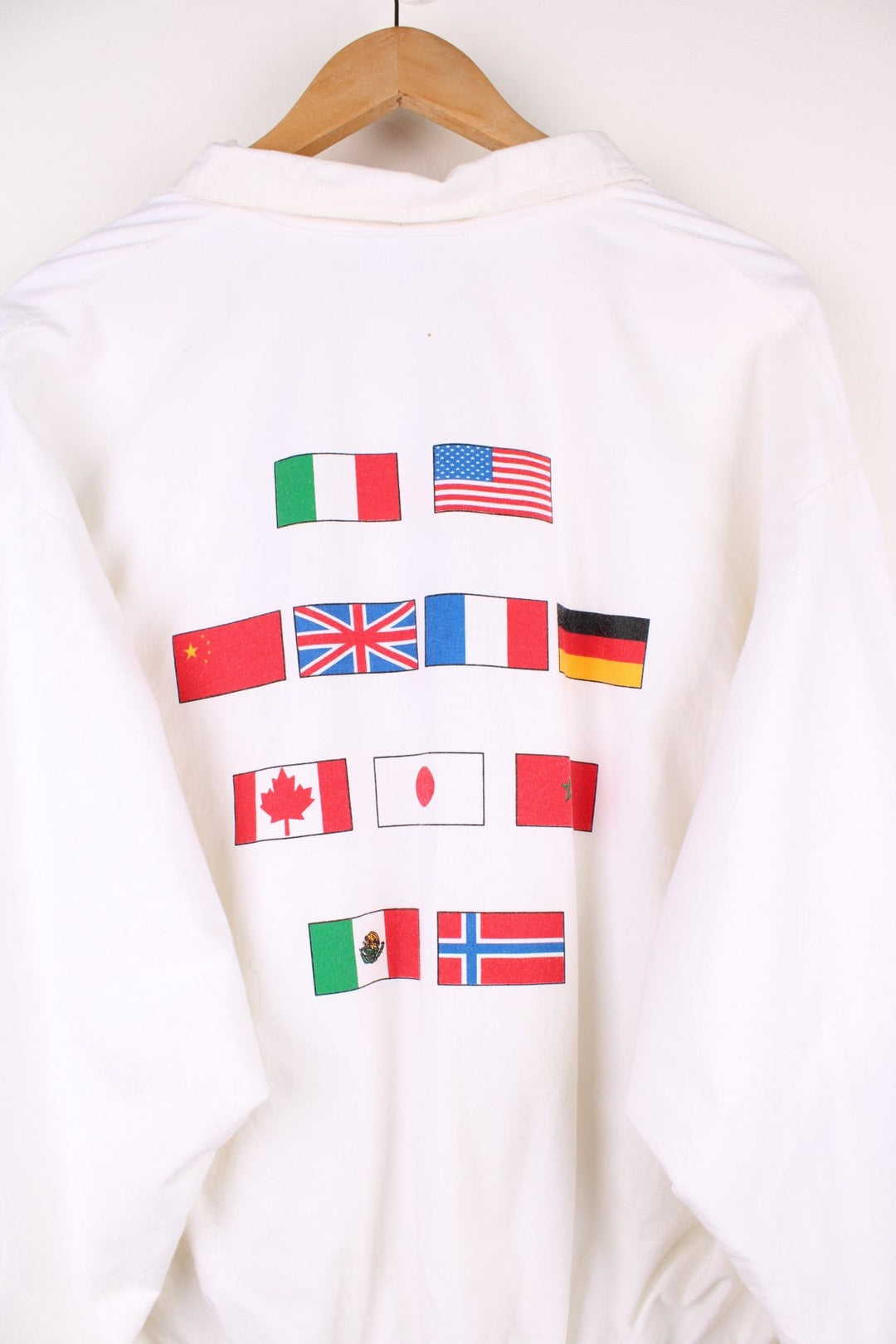 Disney Epcot Center Coach Jacket in a white and black colourway, zip up with side pockets, has a nylon lining, Mickey Mouse and the 'Epcot Centre' spell out printed on the front, and on the back has a variety of countries flag's