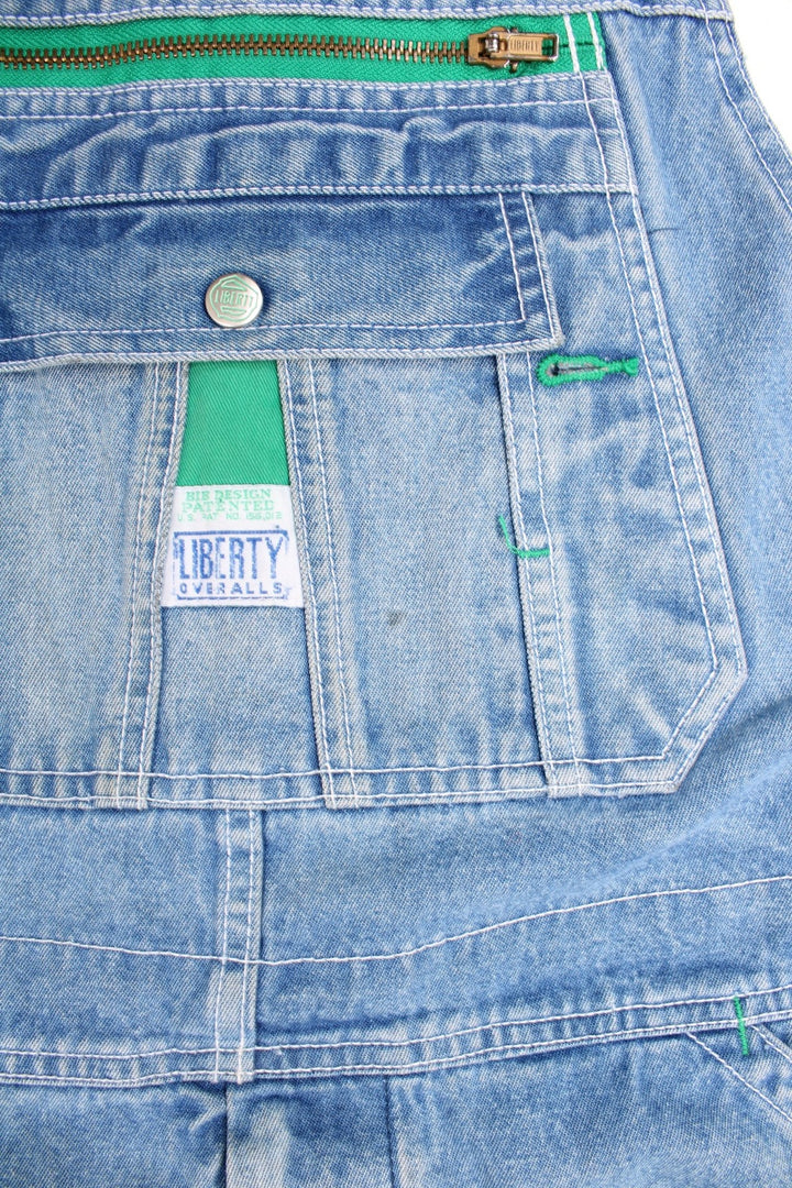 Liberty light wash denim dungarees with green accents, multiple pockets and a hammer loop. 